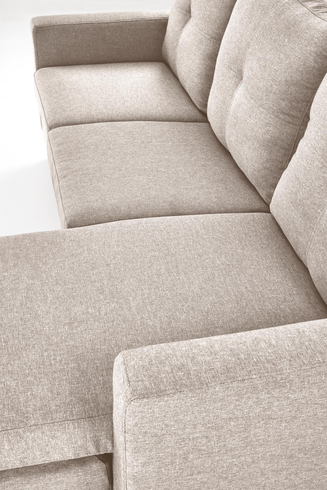 Zbliżenie na beżową tapicerkę sofy GERSON z podnóżkiem.