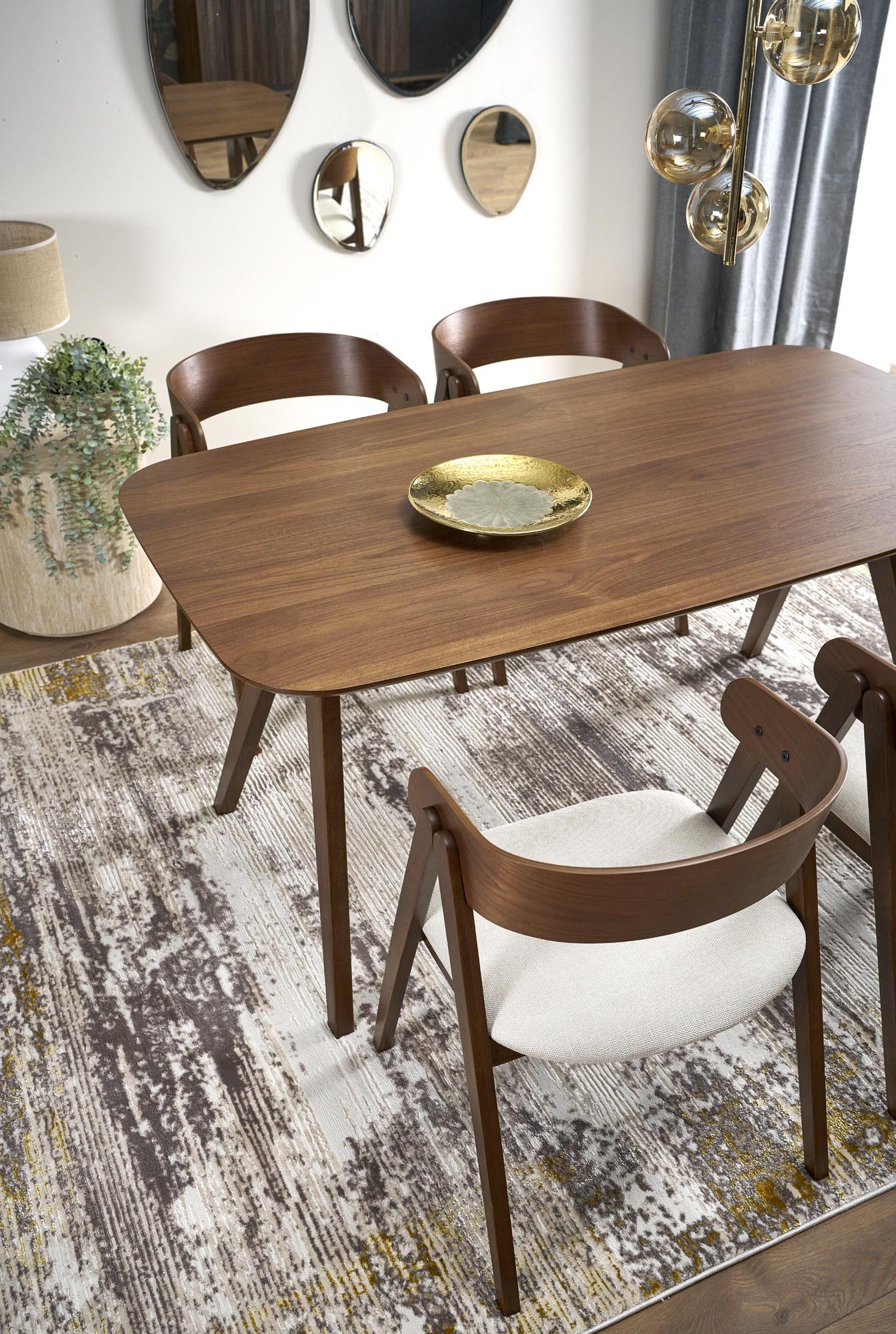 Widok z góry na drewniany stół MIGUEL w kolorze orzechowym z czterema krzesłami na dywanie.